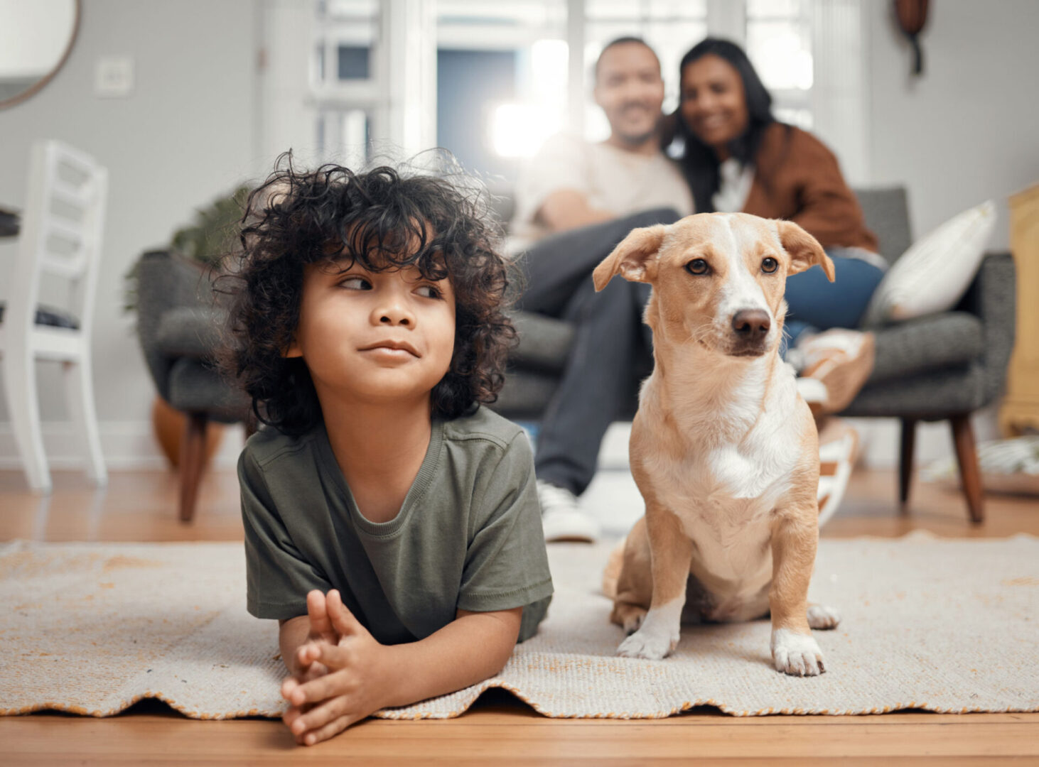 Child and dog on floor, family in background.